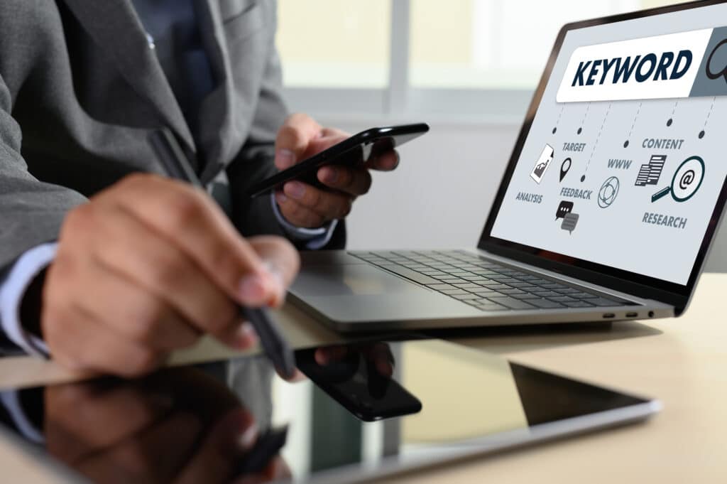 Keywords Research COMMUNICATION research, on-page optimization, seo Man working on a website's keyword research on his laptop, tablet and phone.