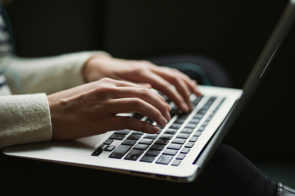kaitlyn-baker-vZJdYl5JVXY-unsplash Woman on her laptop searching for how to improve SEO for her website.